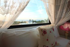 a bedroom with a window with white curtains and a pillow at Min Le Yuan B&B-include long stay in Hualien City