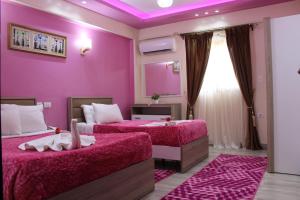 a purple bedroom with two beds and a mirror at Amin Hotel in Cairo