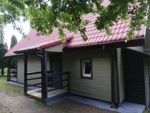 ein Haus mit einem rosa Dach und einer Veranda in der Unterkunft Domek letniskowy Wczasowik 3 in Kruklanki