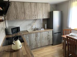 a kitchen with wooden cabinets and a stainless steel refrigerator at Apartament Zalesie in Ostrowo