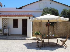 a table with an umbrella in front of a house at La stanza di Vali in Sperlonga