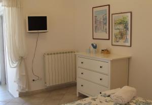 a bedroom with a dresser and a tv on the wall at La stanza di Vali in Sperlonga