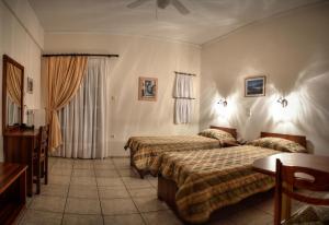 a hotel room with two beds and a table at Vassiliki Studios in Andros