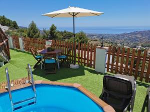a swimming pool with a table and an umbrella at Casa Ayo in Frigiliana