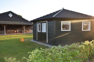 a small black house in a yard next to a house at 't Peelhuisje in Kronenberg
