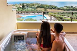 a couple sitting in a hot tub with wine glasses at Hotel Santa Chiara in Capo Vaticano
