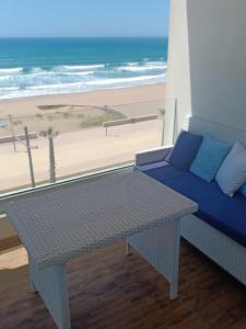 einen Tisch und ein Sofa auf einem Balkon mit Strand in der Unterkunft Mahdia beach in Kenitra