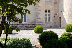 a building with a bench and bushes in front of it at Ferme du Château in Anthenay