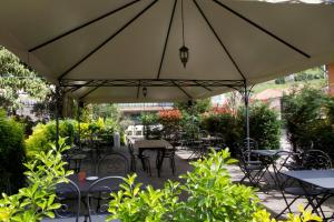 un patio con mesas y sillas bajo una sombrilla grande en Albergo Amici, en Varese Ligure