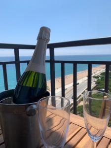 a bottle of wine in a bucket on a table with two glasses at Apartamento primera línea de Mar Enjoy the view in Blanes