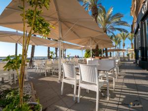 einen Tisch und Stühle mit Sonnenschirm am Strand in der Unterkunft DOS PLAYAS - Torrevieja in Torrevieja