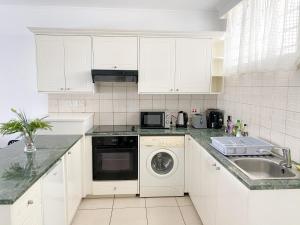 a white kitchen with a sink and a dishwasher at Sea Anemone Apartments in Paphos City