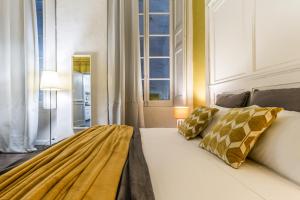 una camera da letto con un letto bianco con cuscini dorati di Family Apartments San Lorenzo a Genova