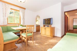a room with a table and chairs and a television at Appartementhaus Schützenhof Schied in Grossarl