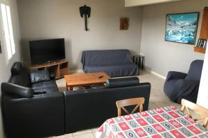 a living room with a black couch and a table at Maison spacieuse in Gruissan