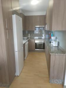 a kitchen with wooden cabinets and a white refrigerator at Nores Buenavista 2 in Vilaboa