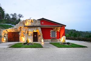 a red barn with a rock wall in front of it at B&B La Casa nella Roccia in Villanova del Battista