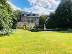 a large house in a field of grass with trees at Manoir de la Marjolaine in Cabourg