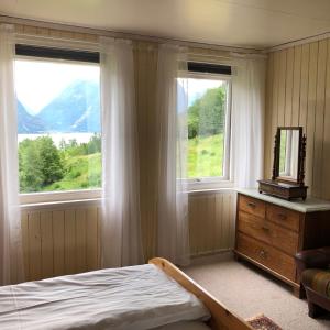 a bedroom with two windows and a bed and a dresser at Tunold Gård - Gamle huset in Mindresunde