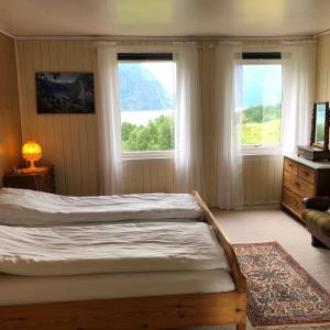 a bedroom with a bed and two windows at Tunold Gård - Gamle huset in Mindresunde