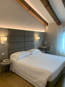 a bedroom with a large white bed and a table at Hotel Bel Soggiorno in San Gimignano
