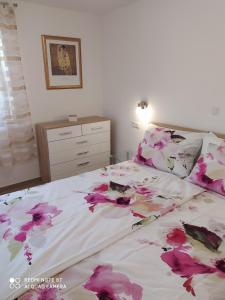 Apartment Bruno في مالي لوسيني: غرفة نوم مع سرير مع زهور وردية عليه