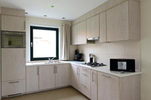 a kitchen with wooden cabinets and a window at Vakantiewoningen t-dorp in Meetkerke