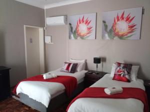 una camera d'albergo con due letti con lenzuola rosse e bianche di Caledon Overnight Rooms a Kimberley