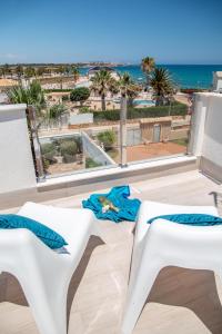 a view of the beach from a balcony with two white benches at Beach Villa Flamenca in Orihuela