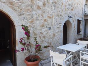 un patio con tavolo, sedie e parete in pietra di Casa di Sofiana by wood and stone ad Ágios Pétros