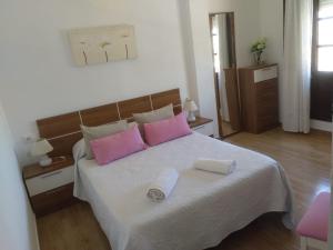 a bedroom with a bed with pink and white pillows at Apartamento Los Jardines San Miguel in Vejer de la Frontera