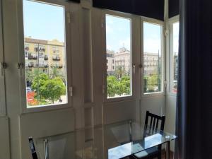 einen Glastisch in einem Zimmer mit Fenstern in der Unterkunft Flats Friends Plaza de la Reina in Valencia
