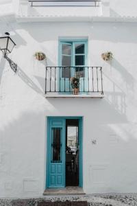 Edificio blanco con puerta azul y balcón en Casa Calle Real 87, en Frigiliana
