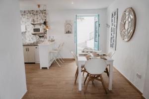 a kitchen and dining room with a white table and chairs at Casa Calle Real 87 in Frigiliana