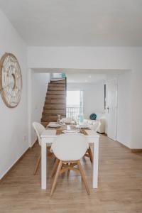 uma sala de jantar branca com uma mesa e cadeiras brancas em Casa Calle Real 87 em Frigiliana
