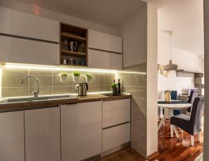 a kitchen with white cabinets and a table with a chair at Apartman Modena Lux in Vrnjačka Banja