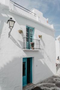 a white building with a blue door and a balcony at Casa Calle Real 87 in Frigiliana