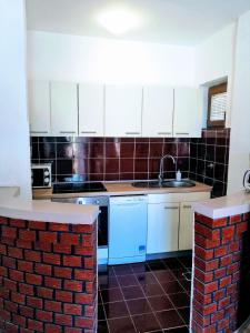 a kitchen with white cabinets and a brick wall at Family Apartments K&M in Pag