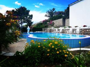 una piscina con sillas y flores en un jardín en Family Apartments K&M, en Pag