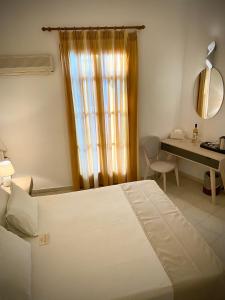a bedroom with a bed and a desk and a window at Asteri Hotel in Livadi