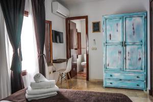 1 dormitorio con cómoda azul y 1 cama con toallas en Hotel Posada de las Cuevas, en Arcos de la Frontera
