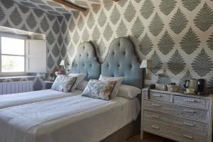 um quarto com 2 camas com uma cabeceira azul e uma cómoda em Hotel Caserio Aldeallana em Segóvia