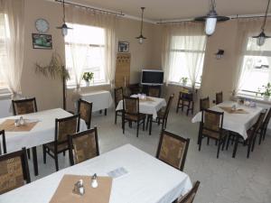 un restaurante con mesas y sillas blancas y ventanas en Korona Panzió, en Levél