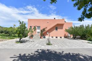 a large pink building with trees in front of it at Bio&B Acquaviva in Otranto