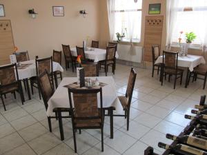 una sala da pranzo con tavoli e sedie bianchi di Korona Panzió a Levél