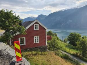 a red house on a hill with mountains in the background at Kvam - Stegastein in Aurland