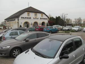 un parcheggio con auto parcheggiate di fronte a un edificio di Korona Panzió a Levél