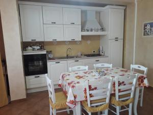 een keuken met een tafel en stoelen en witte kasten bij Residence Rosa in Margherita di Savoia