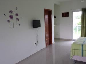 1 dormitorio con 1 cama y TV en la pared en Paraíso do Santinho Apartamentos, en Florianópolis