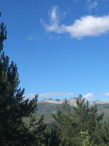 una vista de los árboles y montañas bajo un cielo azul en Artesano I y III, en Navarredonda de Gredos